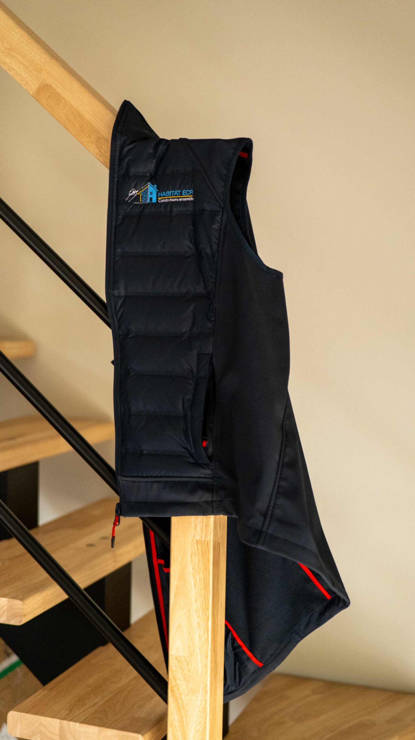 Gilet professionnel brodé Habitat ECR accroché dans un intérieur